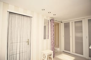 A room with a sliding door, a small table, a wardrobe, and a shower area.