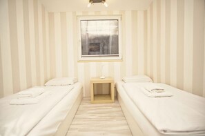 Ein Zimmer mit zwei Einzelbetten, einem kleinen Tisch und einem Fenster.