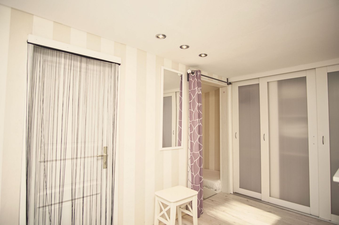 Una habitación con puerta corredera, una mesita, armario y zona de ducha.