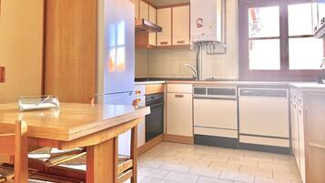 Cocina con armarios de madera, refrigerador, lavavajillas y ventana.