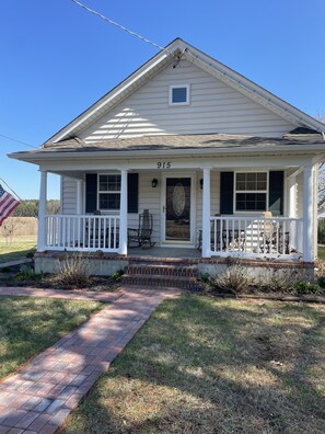 A single-story house with a front porch, a mailbox, and a number "915" on the door.