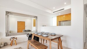 A dining area with a wooden table set for six, a bench, and a large mirror above. - Bellevue Hill Designer, Beaches, City & Views (Bellevue Hill)