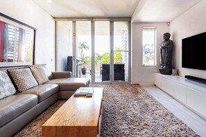 Un salon moderne avec un canapé en cuir, une table basse en bois et un grand téléviseur à écran plat.