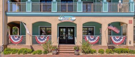 A two-story building with a balcony, a market cafe sign, and American flags.