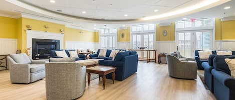 Un salon spacieux doté de plusieurs canapés et fauteuils, d’une cheminée et de grandes fenêtres.