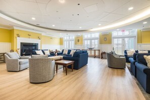 A spacious living room with multiple sofas and armchairs, a fireplace, and large windows. - Mini Weeks Stays Available Sunset Island 37 Founta (Ocean City)