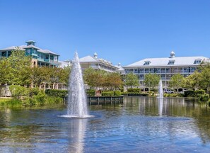 A building with a fountain in front, surrounded by trees and a clear sky.