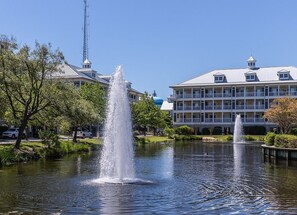 A hotel with a fountain in the courtyard, surrounded by trees and a body of water. - Mini Weeks Stays Available Sunset Island 37 Founta (Ocean City)