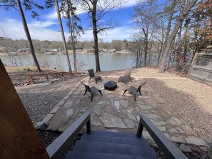 Une terrasse en pierre avec des sièges extérieurs et une vue sur un lac.