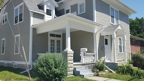 A two-story house with a porch, a front door, and a small front yard. - Cozy vintage getaway minutes from downtown! (Lincoln)