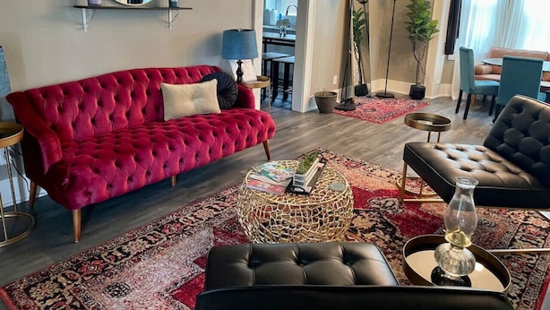 A living room with a red sofa, a black sofa, a coffee table, and a floor lamp. - Cozy vintage getaway minutes from downtown! (Lincoln)