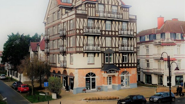Ein traditionelles Fachwerkhäus mit mehreren Balkonen, einem Laden im Erdgeschoss und einem gut sichtbaren Eingang.