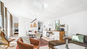 Un salon moderne comprenant un coin repas, une cuisine et une grande fenêtre.