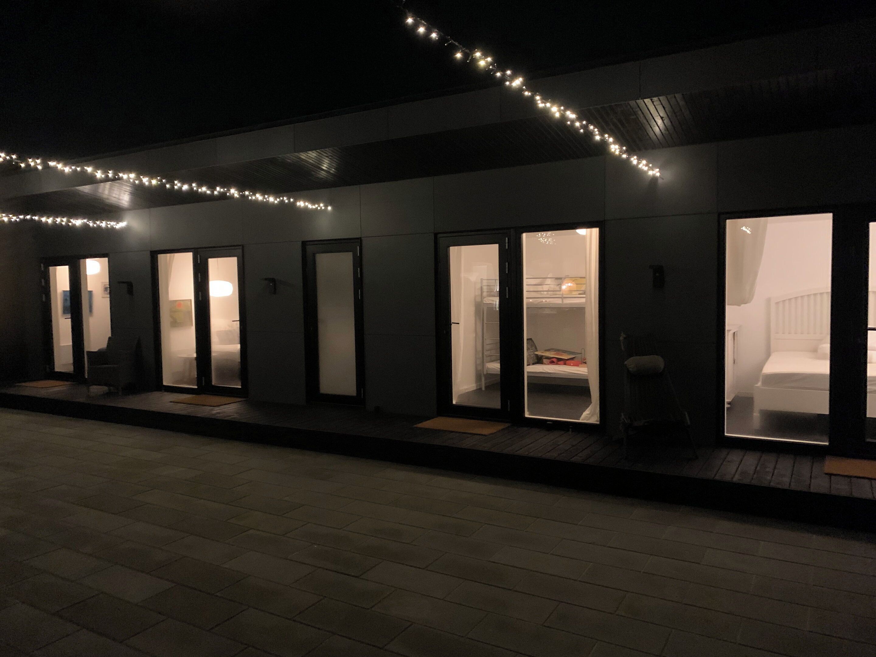 Une rangée de chambres d’hôtel dotées de portes coulissantes, chacune comprenant un lit et une petite table.