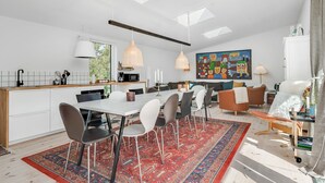 Une cuisine moderne avec un coin repas, une grande moquette et un tableau coloré au mur.
