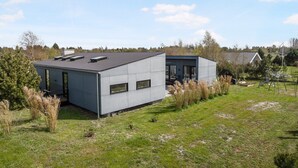 Un bâtiment moderne doté d’un toit plat, de grandes fenêtres et d’une petite structure adjacente.