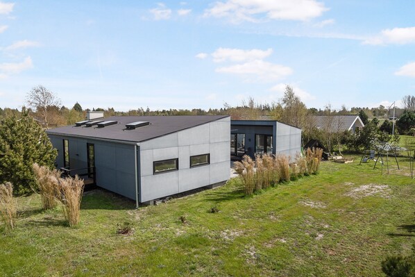 A modern building with a flat roof, large windows, and a small attached structure. - Unique and modern holiday home in Marielyst (Væggerløse)
