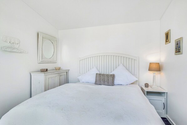 A neatly arranged bedroom with a bed, bedside table, and a dresser. - Unique and modern holiday home in Marielyst (Væggerløse)