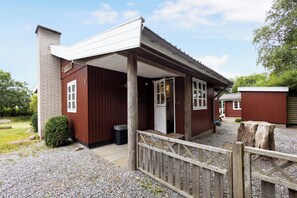 Een houten gebouw met een overdekte veranda, een deur en een klein raam.