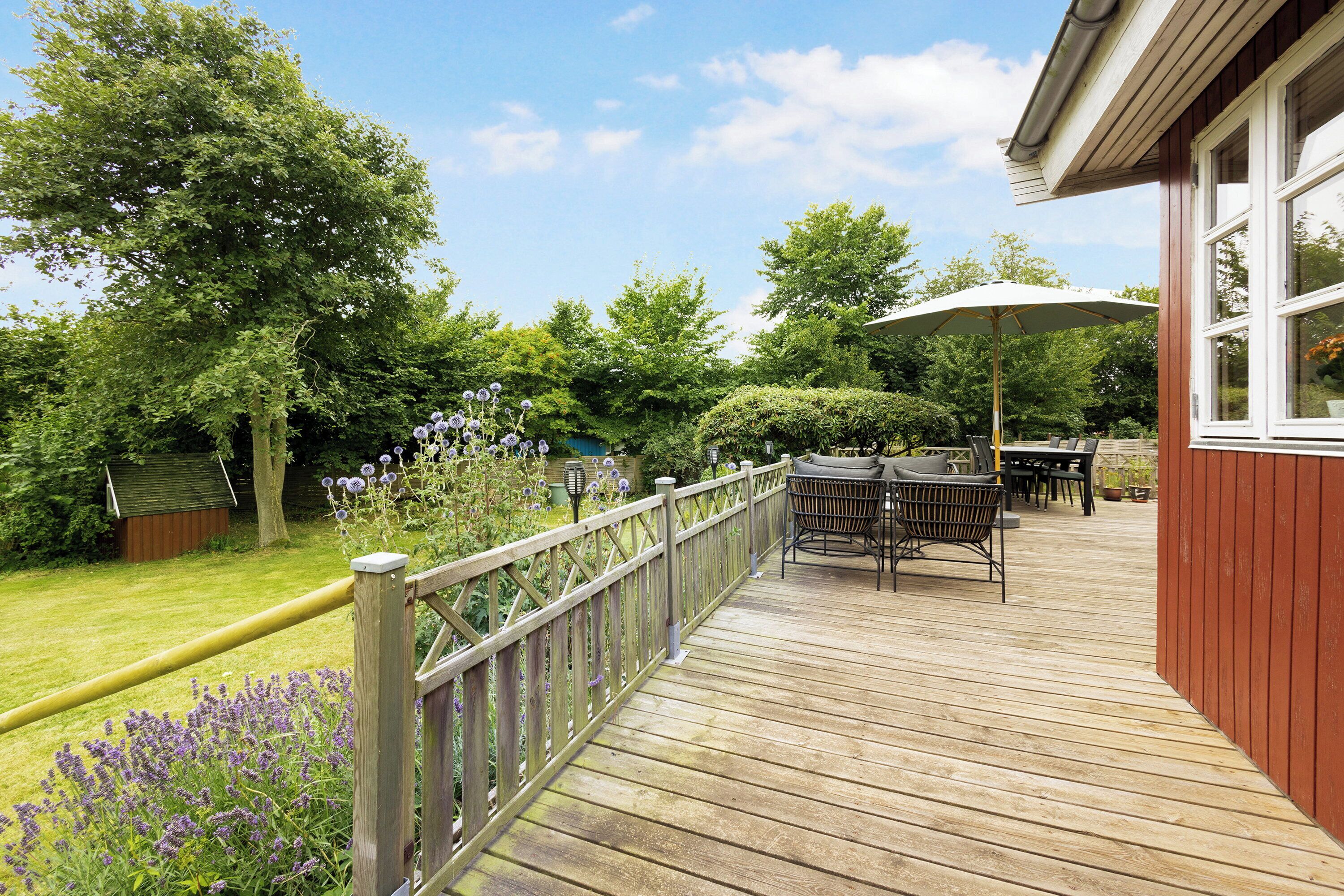 A wooden deck with outdoor furniture, a table, and a chair.