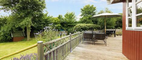 A wooden deck with outdoor furniture, a table, and a chair.