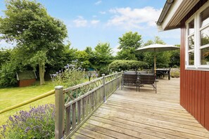 Eine Holzterrasse mit Gartenmöbeln, einem Tisch und einem Stuhl.