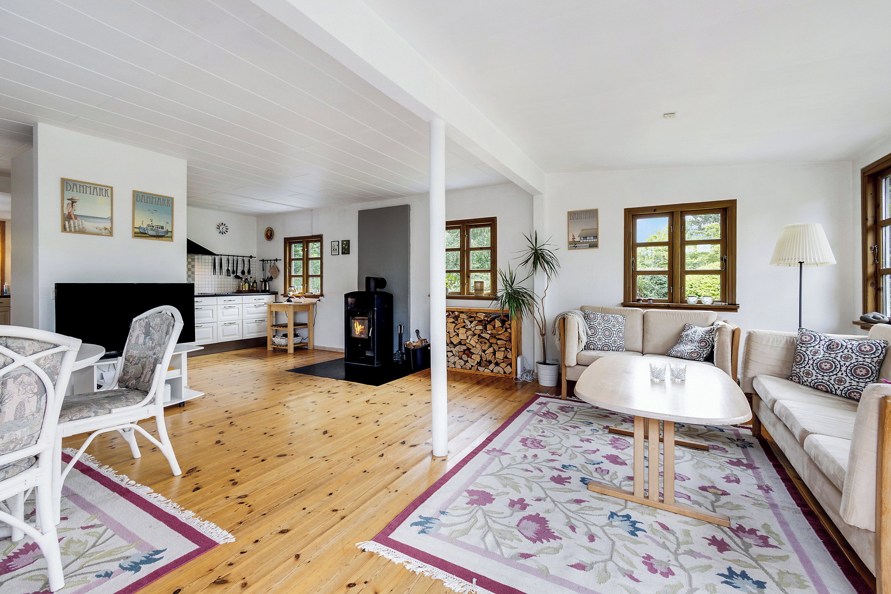 A spacious living room with a fireplace, wooden flooring, a sofa set, and a dining area with chairs.