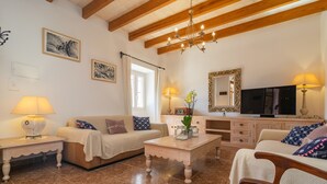 A cozy living room with a wooden ceiling, a television, and a dining area with a table and chairs. - NA BURGUERA - Wonderful villa with private pool and free WiFi. (Santanyí)