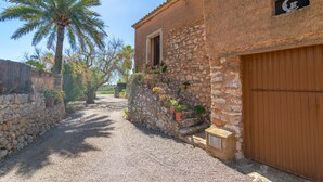 A narrow cobblestone street flanked by stone buildings with a wooden door and a window with a crescent moon decoration. - NA BURGUERA - Wonderful villa with private pool and free WiFi. (Santanyí)