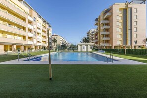 Guests can enjoy a refreshing swim in the central pool surrounded by lush artificial grass and a secure fence.