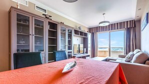 Een hotelkamer met een groot bed, een eettafel, een bank en uitzicht op de stad.