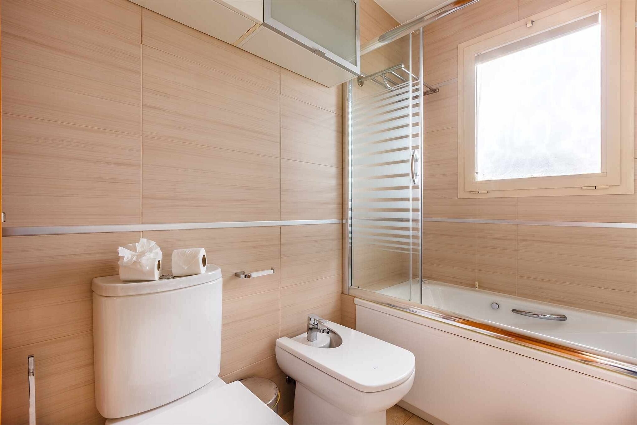 Een moderne badkamer met toilet, bidet en bad.