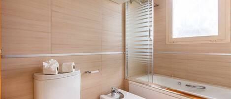 Een moderne badkamer met toilet, bidet en bad.