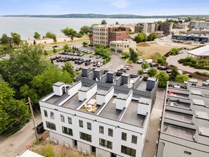 A modern building with a flat roof, large windows, and a parking lot in front. - BRAND NEW downtown rooftop condo with water views (Traverse City)