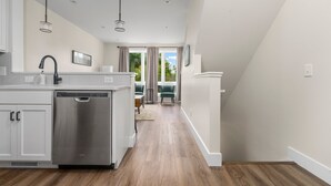 Une cuisine moderne avec des meubles blancs, des appareils électroménagers en acier inoxydable et un plancher en bois.