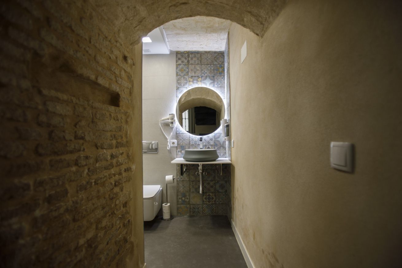A narrow hallway leading to a bathroom with a toilet, sink, and a tiled backsplash.