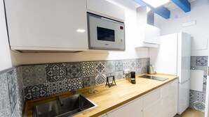 Une cuisine moderne dotée d’un four à micro-ondes encastré, d’un évier et de carreaux décoratifs sur le mur derrière l’évier.