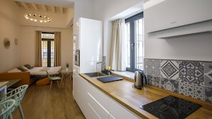 Una cocina compacta con ventana, un lavamanos y una tetera sobre la encimera.