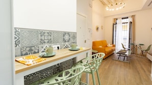Una cocina moderna con baldosas estampadas, encimera de madera y una zona de bar con sillas verdes.