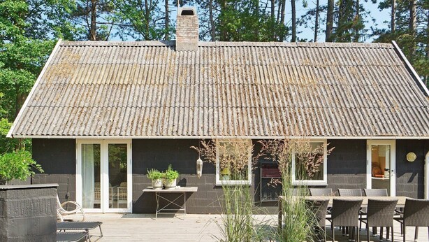 A house with a tiled roof, a porch with outdoor furniture, and potted plants.