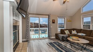 Ein geräumiges Wohnzimmer mit großem Fenster, Deckenventilator und Kamin.