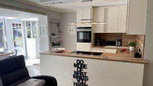 Et moderne køkken med en central ø, hvide skabe og en inspirerende tekst på væggen.