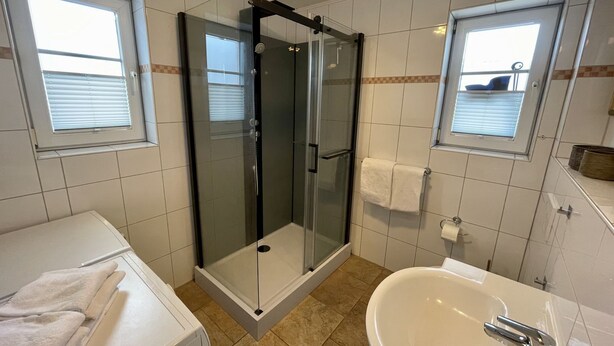 A modern bathroom with a glass-enclosed shower, a white sink, and a toilet. - Lille Hygge Hüs - Luxus-app., Strandnah für 2 Pers. mit Terrasse, Stellplatz, Wlan. 1 Haustier (Sylt)