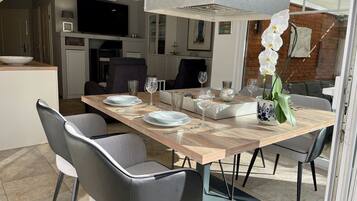 A modern dining area with a wooden table, grey chairs, and a unique ceiling light fixture.