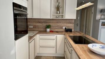 A modern kitchen with white cabinets, a wooden countertop, a built-in oven, and a sink.