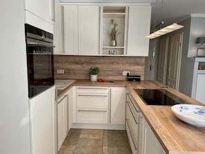 Eine moderne Küche mit weißen Schränken, einer Holz Arbeitsplatte, einem eingebauten Ofen und einem Spülbecken.