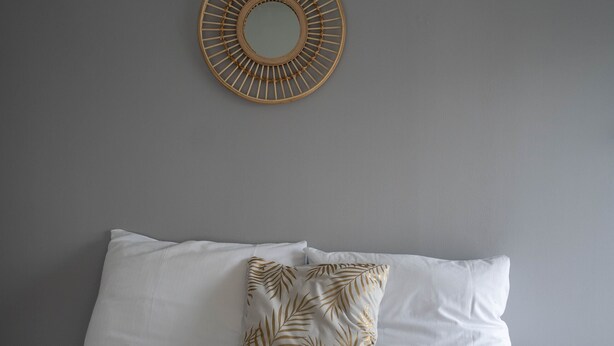 A neatly made bed with white linens, a brown throw blanket, and a decorative wall mirror. - In Heart of Stavanger BnB with Billiard & Sauna (Stavanger)
