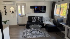 Uma sala de estar moderna com televisão de tela plana, um sofá, uma mesa de centro e uma janela com cortinas.