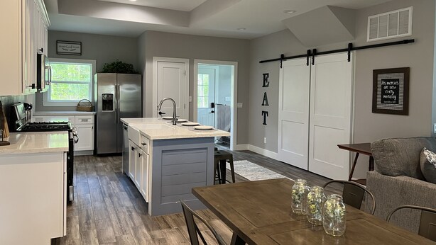 Eine moderne Küche mit Kochinsel, einem Essbereich mit Holztisch und einem Wohnbereich mit Sofa.