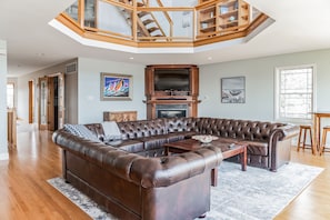 A spacious living room with a large sectional sofa, a fireplace, and a wooden ceiling structure.